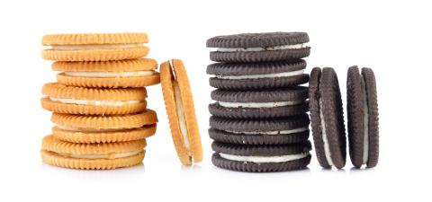 Two stacks of sandwich cookies. One stack are yellow cookies and the other are brown chocolate cookies.