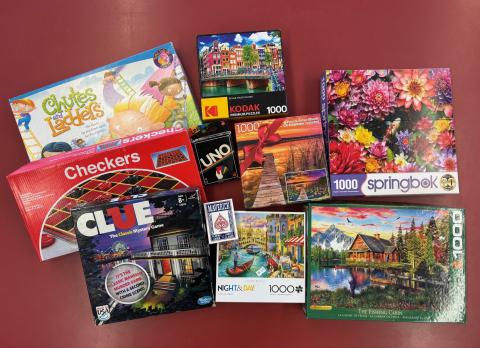 A variety of card & board games, next to several jigsaw puzzles.