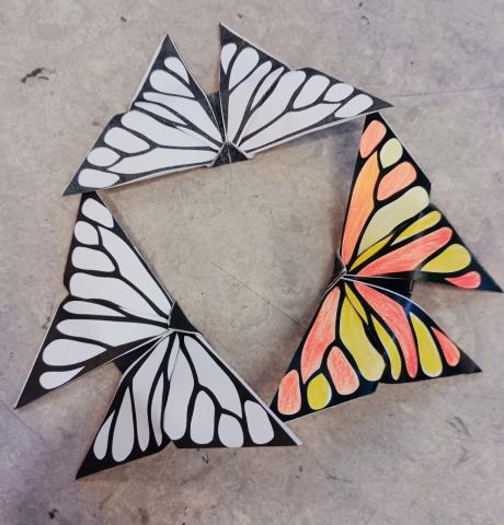 3 butterflies with wing tips touching, one is colored orange and yellow