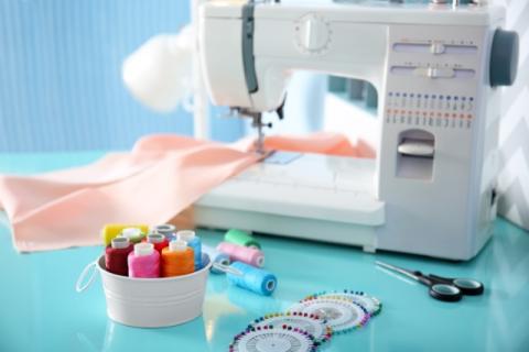 Photo of a white sewing machine surrounded by sewing supplies