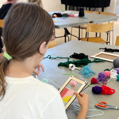 girl works on her many-colored weaving project