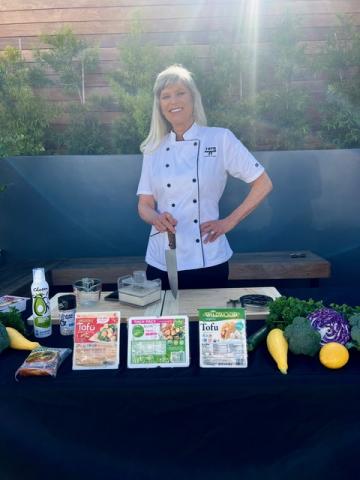 Photo of Chef Liz with table of food prep items in front of her