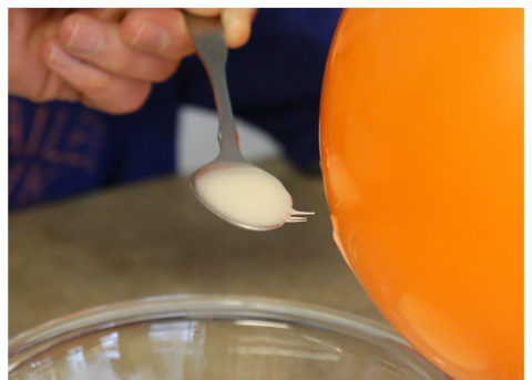 Positively charged cornstarch moving towards a negatively charged balloon 