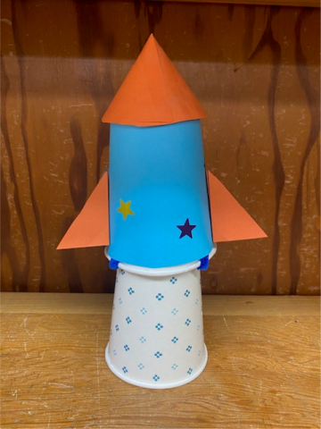 Blue and orange paper cup rocket sitting on paper cup launcher