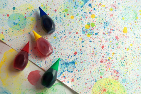 Four bottles of colored bubble solution and a sheet of paper with spots of different colors and sizes