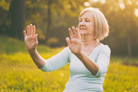 Lone woman doing tai chi outdoors.
