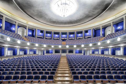 Inside a theater with rows of blue chairs