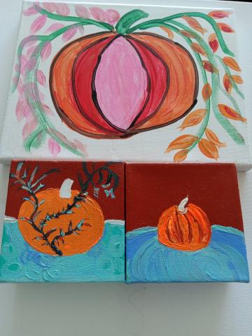 This month's craft will be painting pictures of pumpkins, with the provided image being three pumpkin paintings on canvas. The top image shows a pink, red, and orange striped pumpkin with leaves coming from its stem. The lower left painting is of a pumpkin behind a tree branch on a red and teal background. The right bottom painting is of a pumpkin sinking into the teal group with a red horizon behind it.