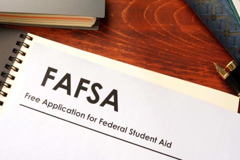 Desk with book and stack of papers labelled "FAFSA" on it