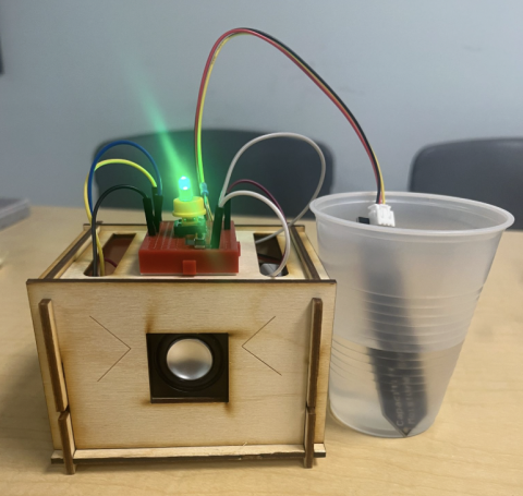 wood and wire device with LED light and a cup of water