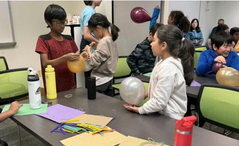 Students working with balloons and other materials to perform science experiments