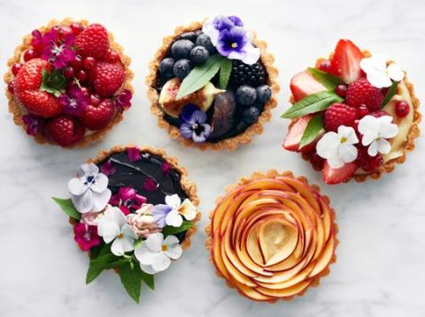 Image of five tarts with edible flowers decorated on top.