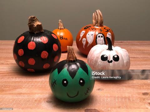 5 pumpkins all painted in different halloween styles, ghost, frankenstine, black with spots