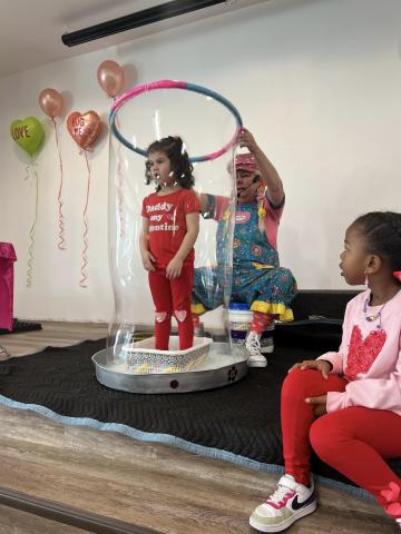 Sparkles the Clown creating a large bubble with a girl inside.