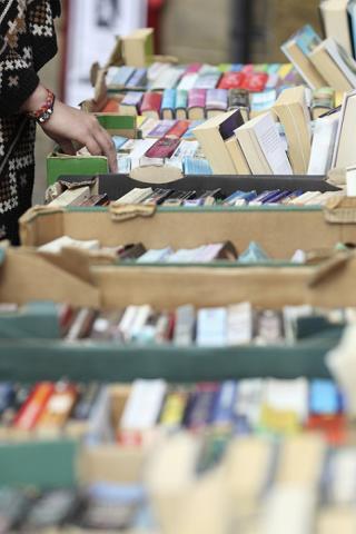 person's hand browsing used books on a library cart