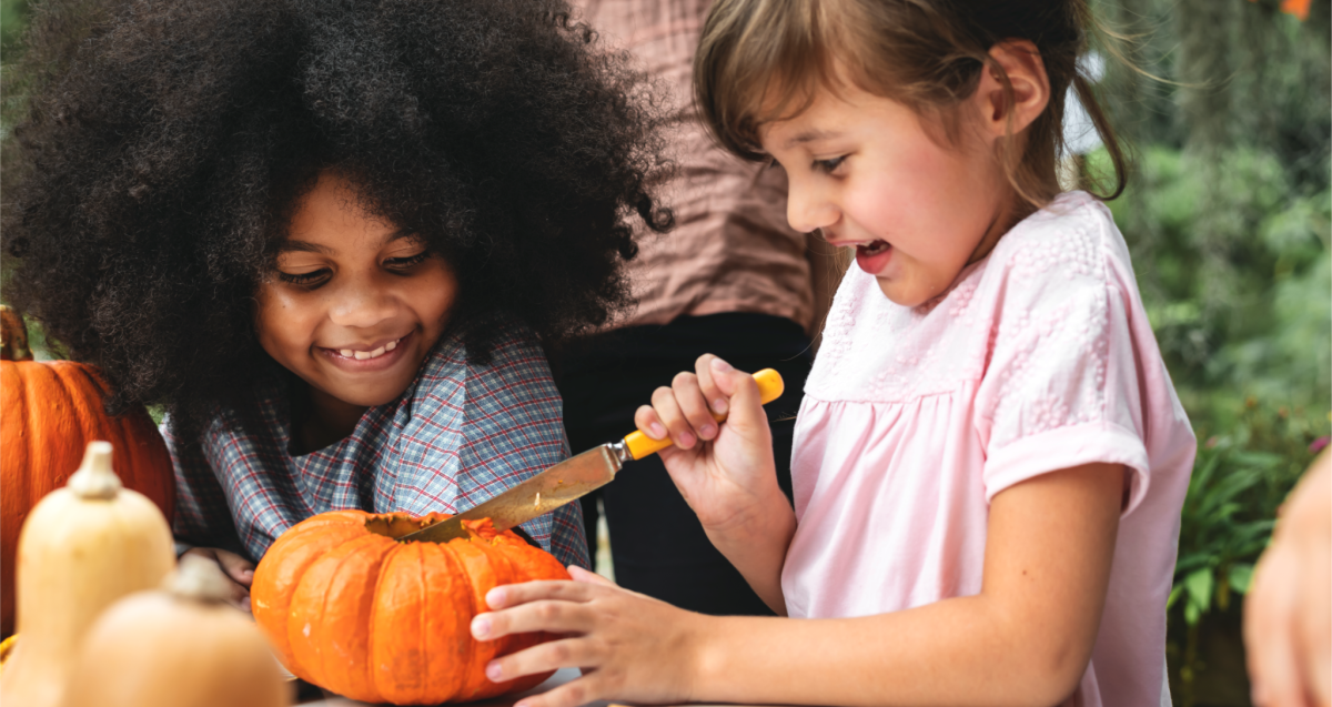 Two girls carving a pumpkin.