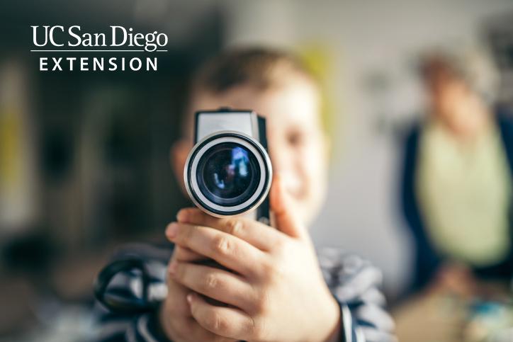 A boy is holding a video camera pointed at the viewer