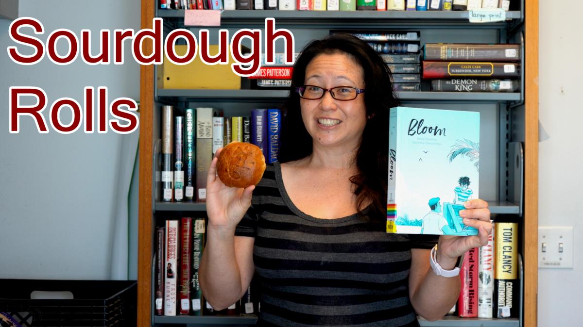 Woman holding a sourdough roll and a copy of the book "Bloom"