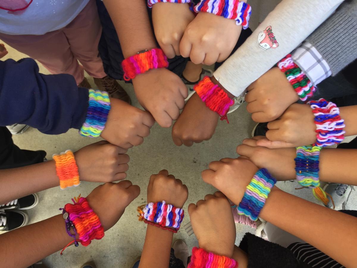 Participants showing off their yarn-wrapped straw weave bracelets in a circle.
