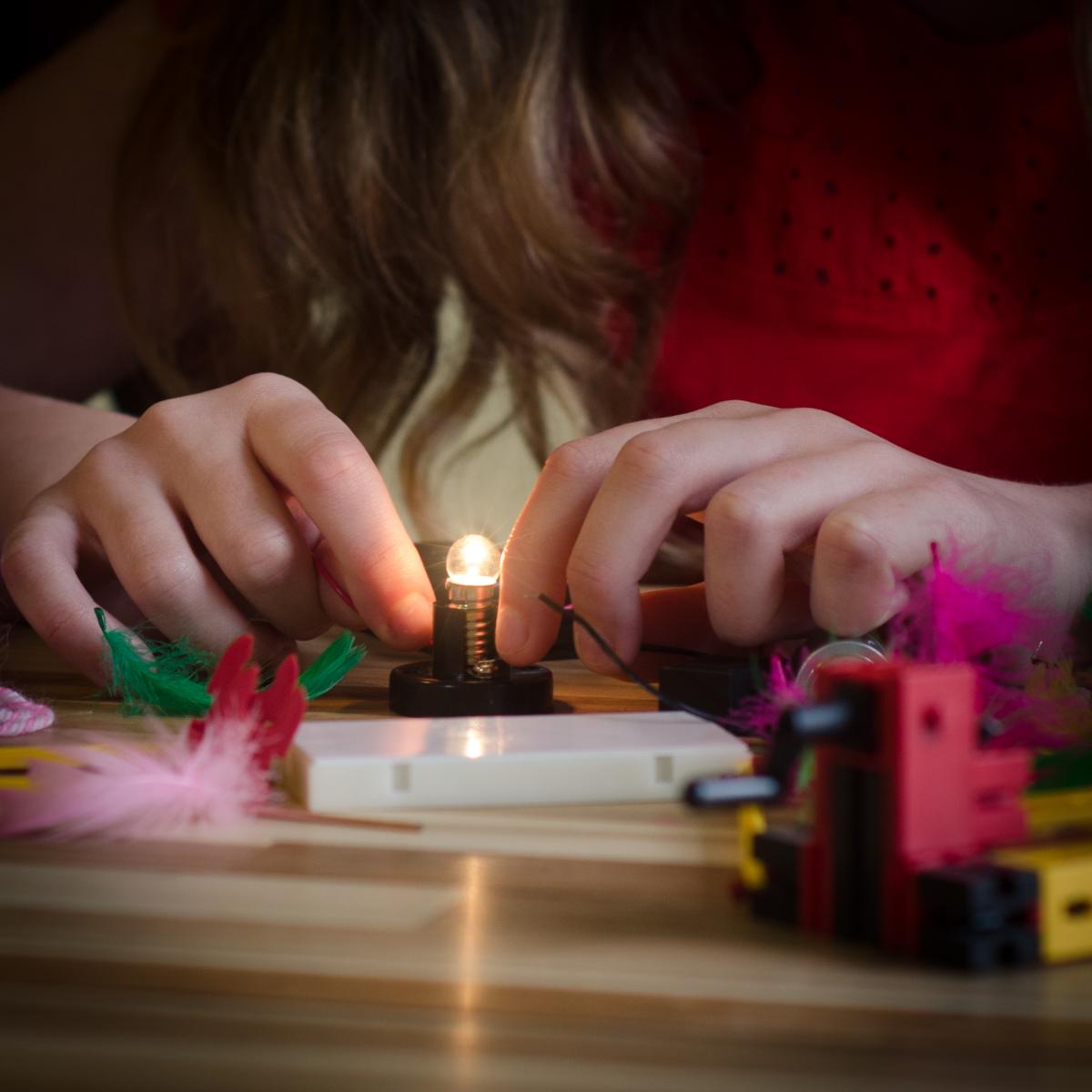 A young person's hands touching a light bulb