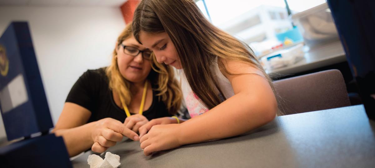 Two girls sitting at table looking at a slimy sea creature