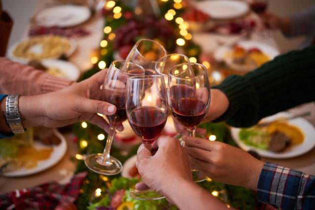 Four people touching wine glasses together.