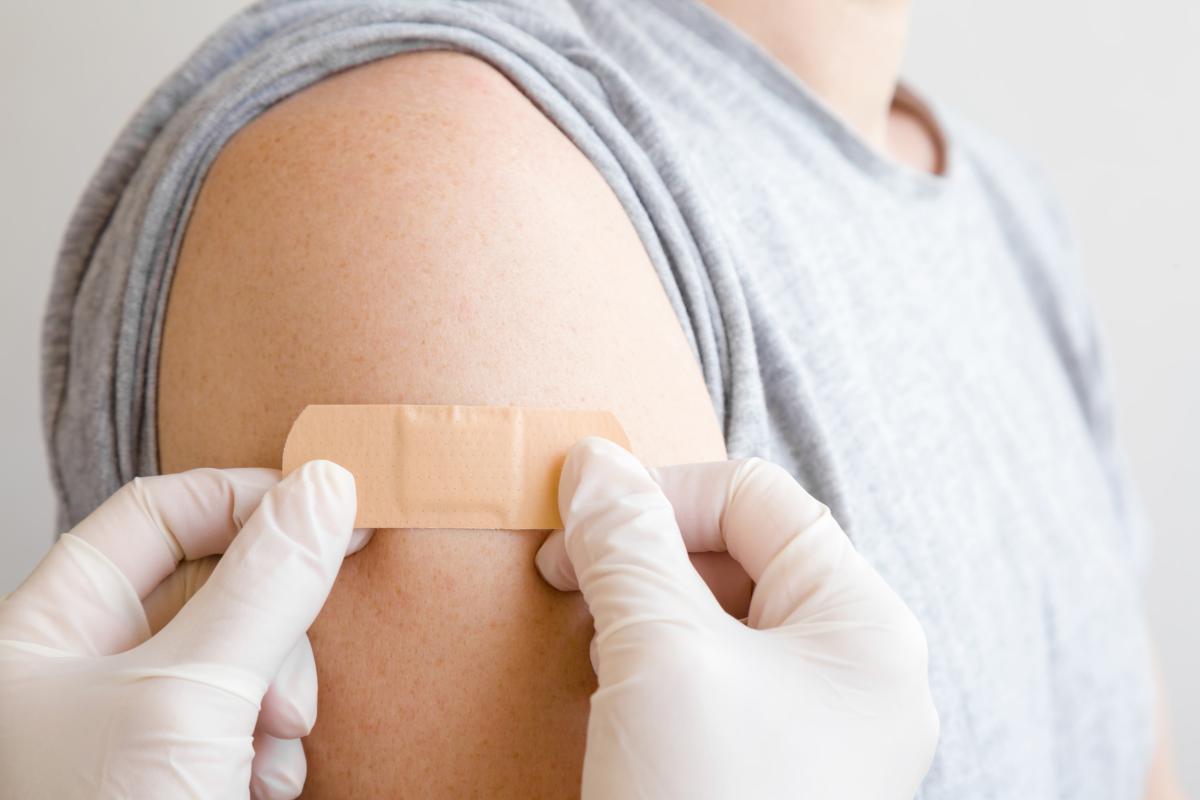 image of gloved hands placing band aid on a person's arm