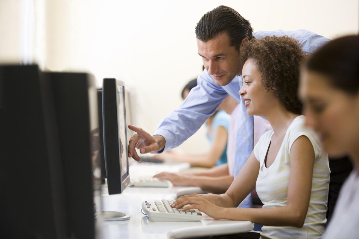 man looking over woman's shoulder as they both look at a computer screen