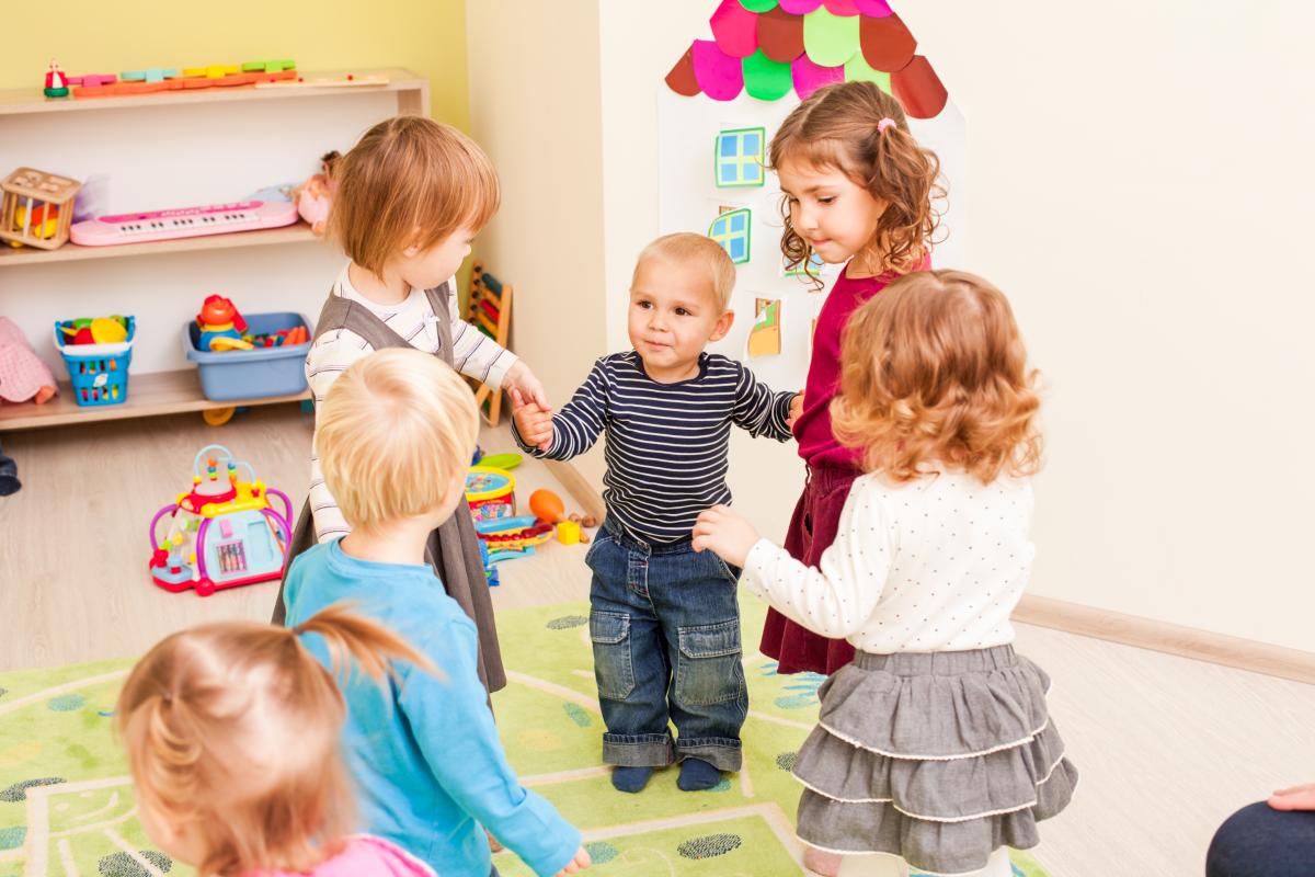 Children stand in a circle holding hands