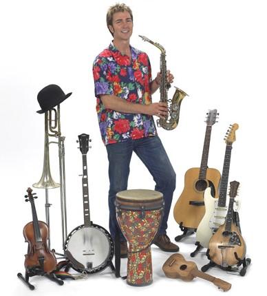 Craig Newton holds a saxophone and is surrounded by other instruments.