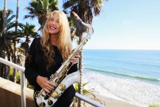 Adrienne Nims holding a saxophone near a beach