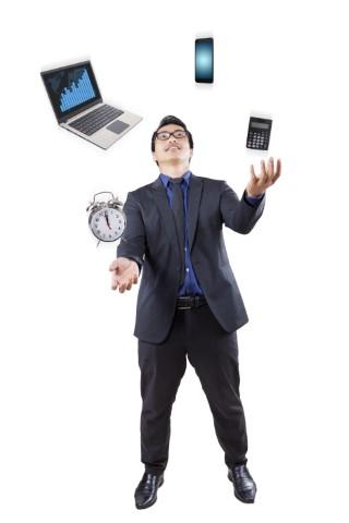 Man juggles a laptop, cell phone, clock, and calculator