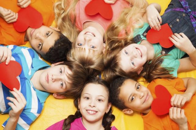 Kids laying in circle with cut out hearts in their hands