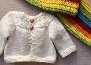 A small sweater and colorful scarf by artists from the Knit and Crochet Circle.