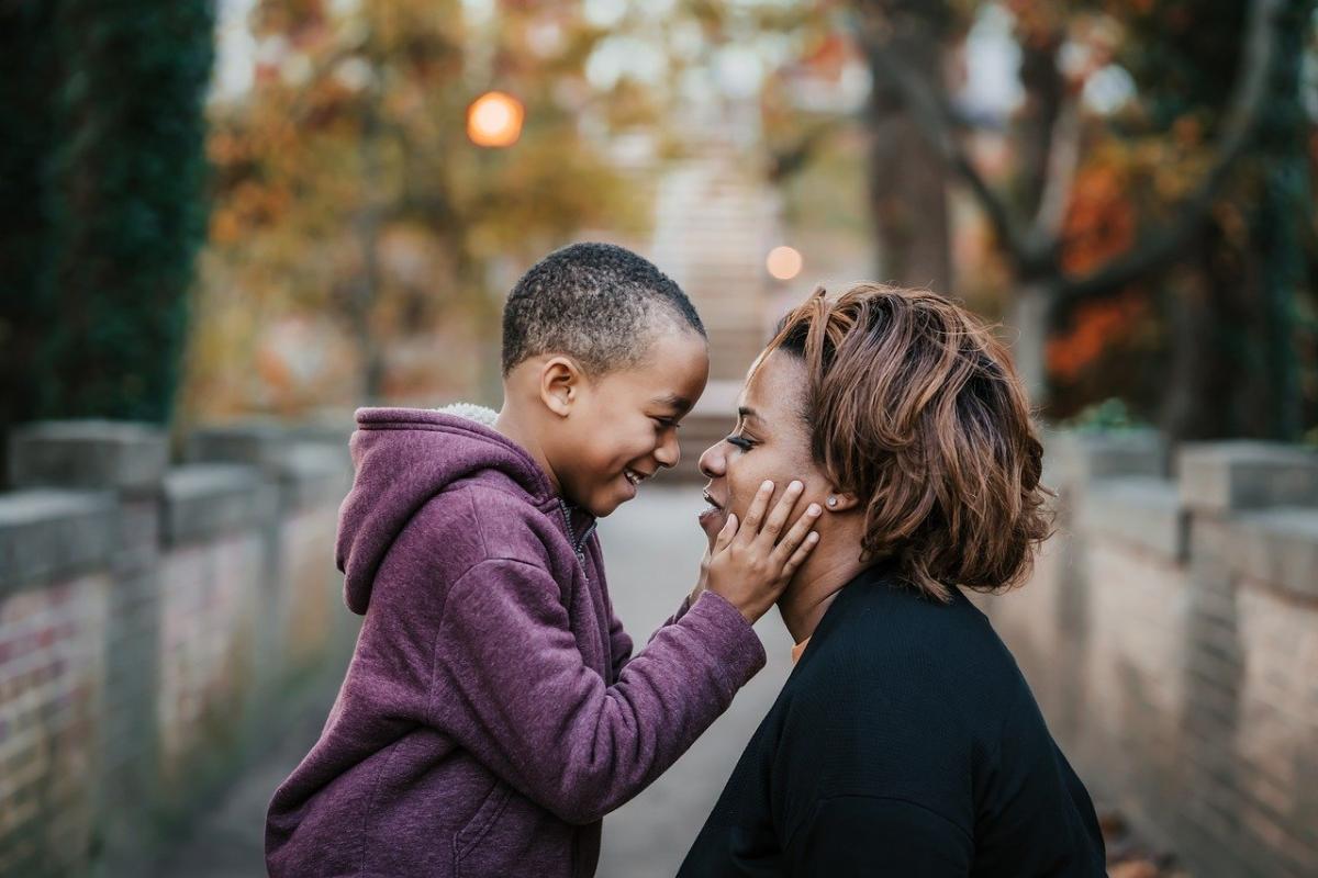 Mom and young son, head to head, smiling on a bridge