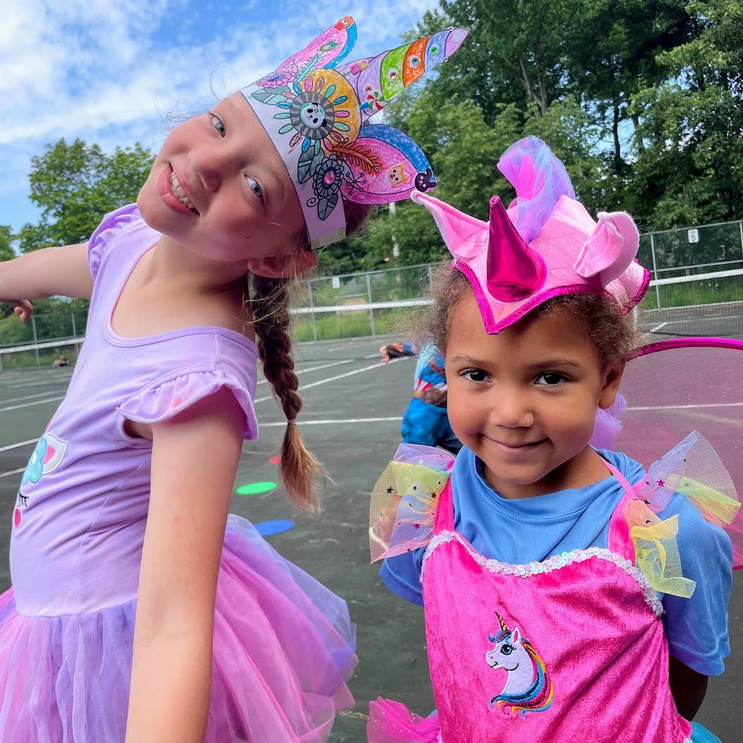 Two girls in pink outfits wearing unicorn crowns