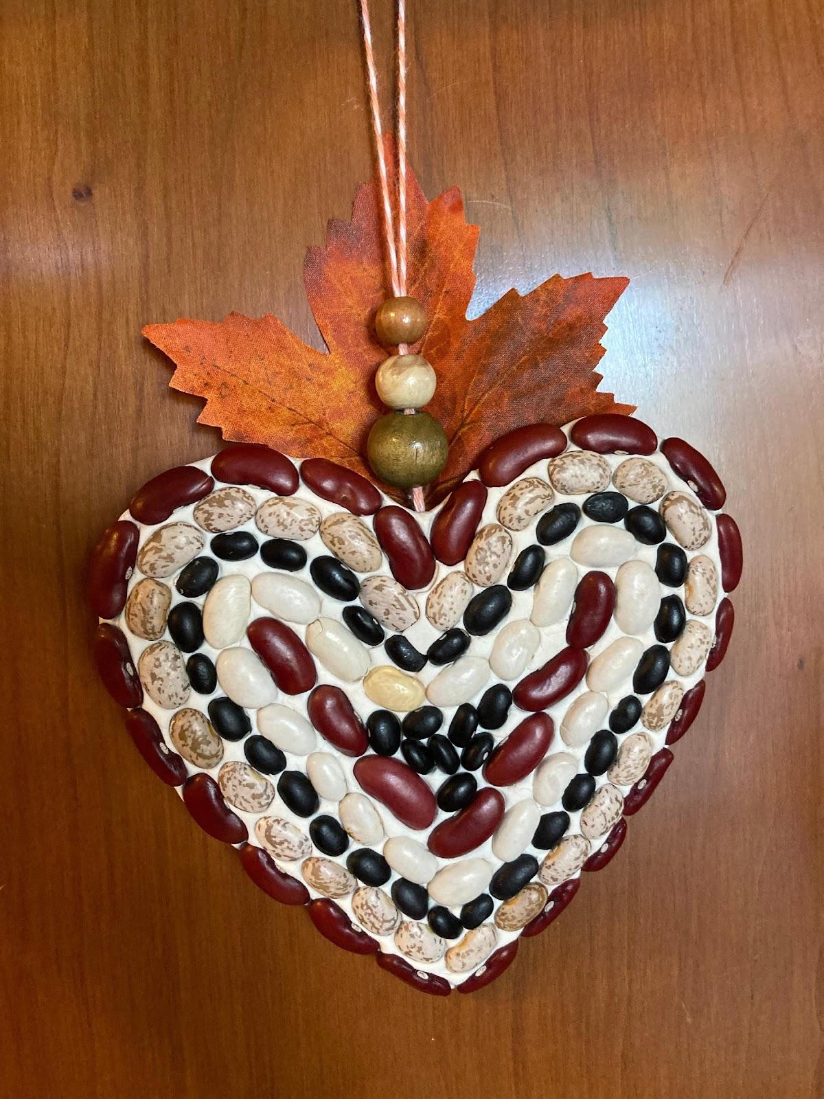 Sample of a bean mosaic in a heart shape with orange fall leaf