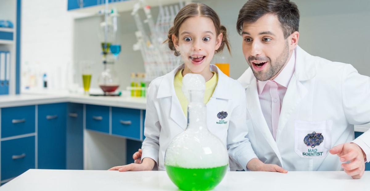 Scientist with Child in front of beaker with green liquid.