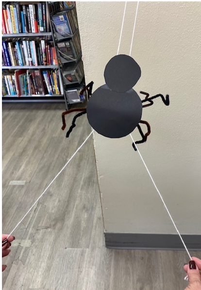 Paper spider sliding up a string