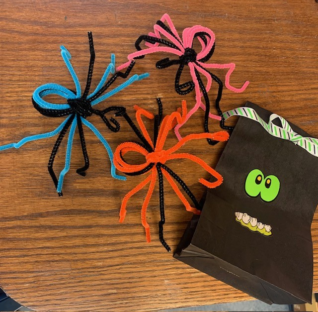 Spiders made from pipe cleaners and a goodie bag with a face illustration on it