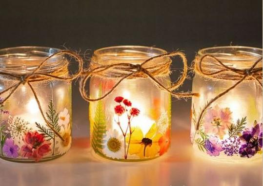 Three glass candle holders decorated with pressed flowers. 