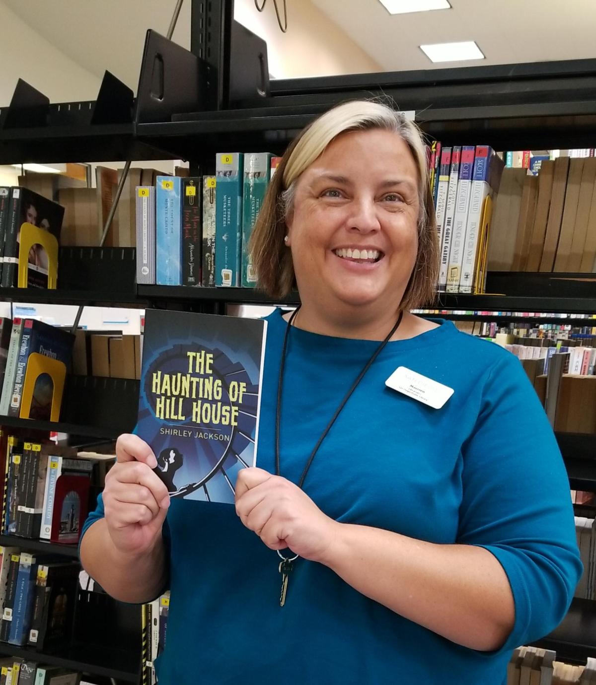 Maureen holding a book with bookshelves behind her