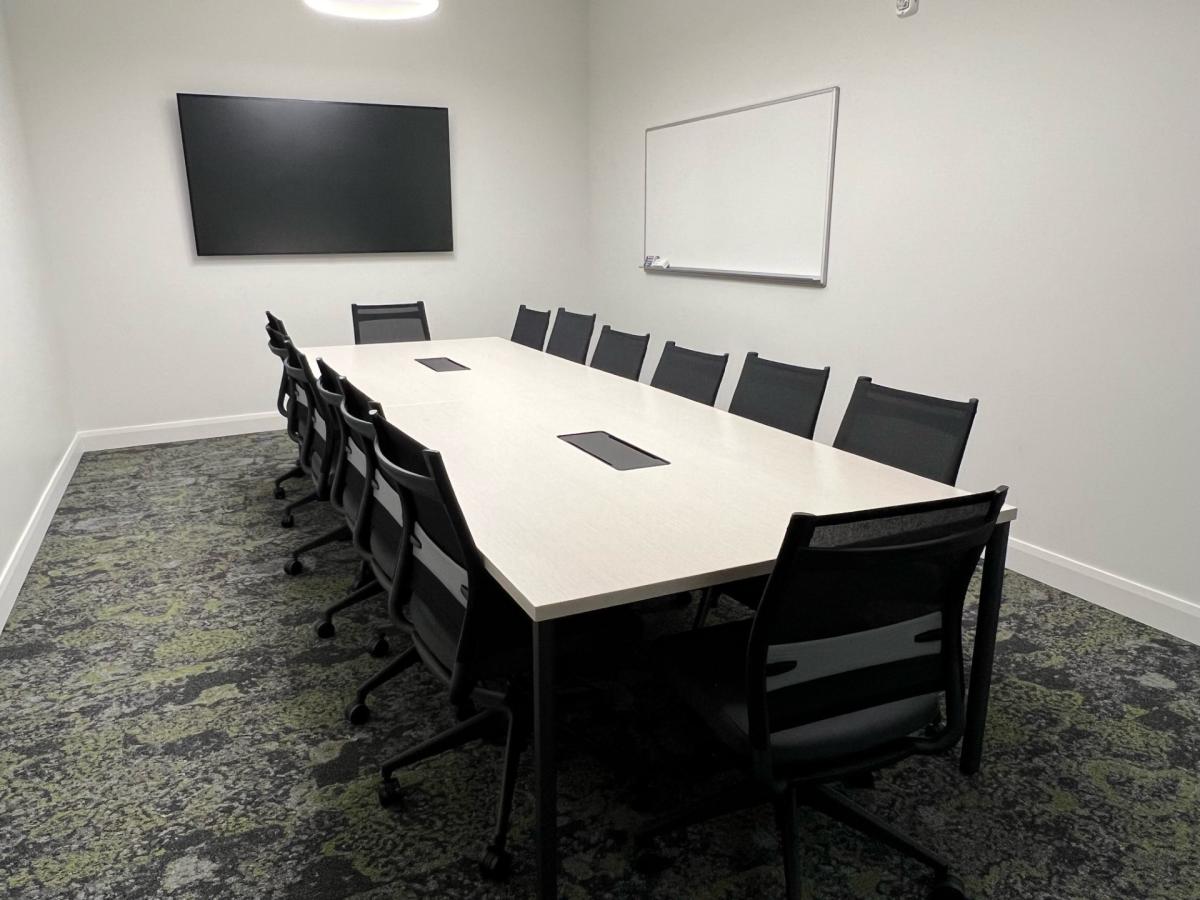 Room with table and chairs, LCD screen, and white board