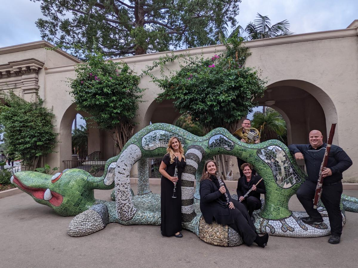 Members of Left Coast Quintet standing in front of a sculpture at Balboa Park