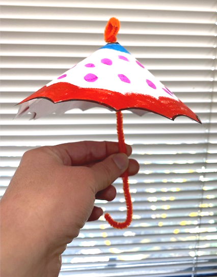 Small, colorful umbrella made out of paper and a pipe cleaner