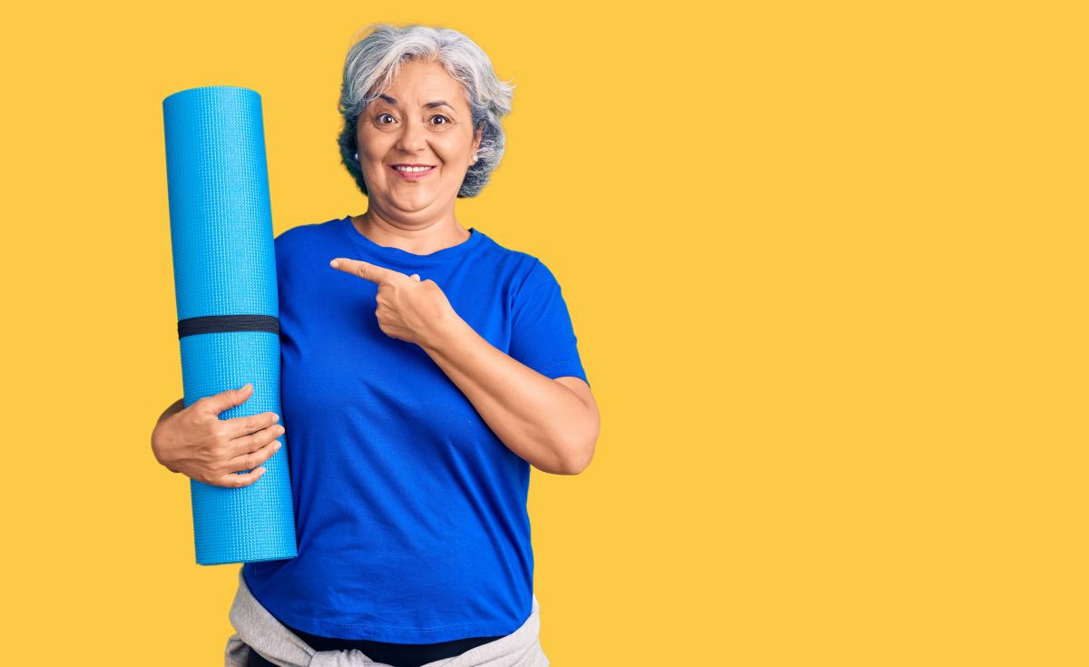 Woman with yoga mat on yellow background.