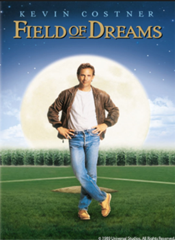 Photograph of a man standing in a baseball field with a cornfield in the background.