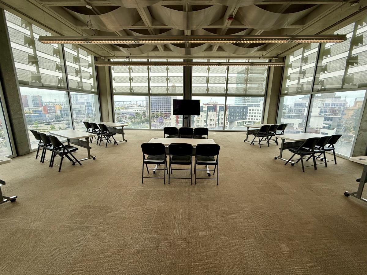 Meeting room with tables, chairs, and a TV