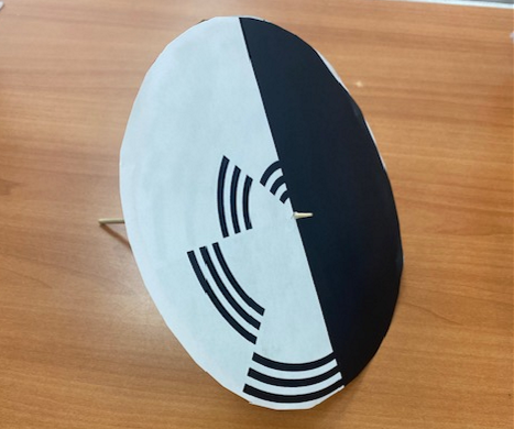 Example of a Benham's disc made out of paper, cardboard, and a wooden skewer