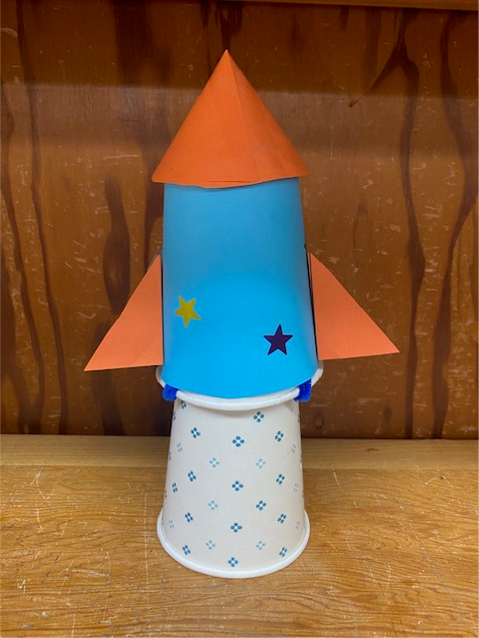 Blue and orange paper cup rocket sitting on paper cup launcher
